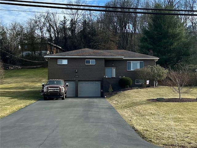 view of front facade with a garage, driveway, a front yard, and brick siding