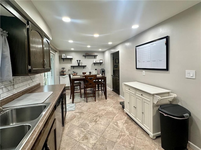 kitchen featuring recessed lighting, decorative backsplash, a sink, dishwasher, and baseboards