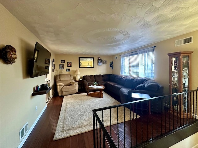 living room with visible vents, baseboards, and wood finished floors