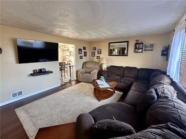 living room with visible vents, baseboards, and wood finished floors