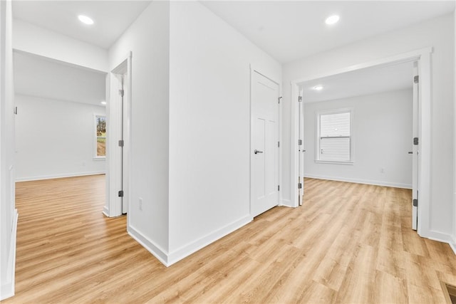 hallway with light wood finished floors, baseboards, and recessed lighting