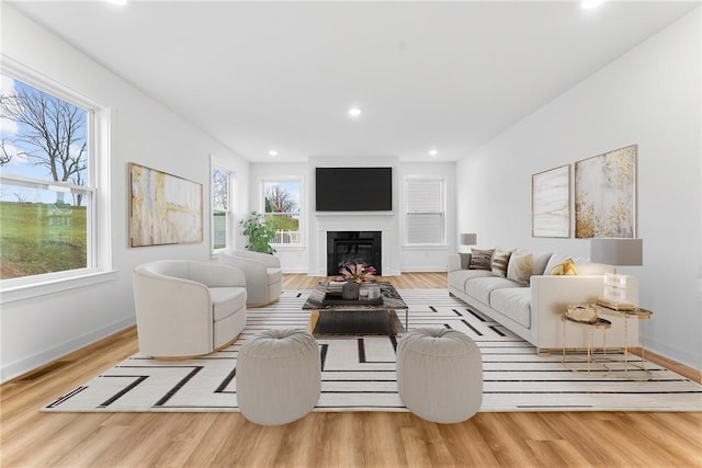 living area with recessed lighting, visible vents, a glass covered fireplace, wood finished floors, and baseboards