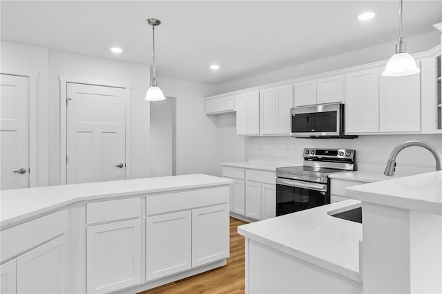 kitchen with stainless steel appliances, light countertops, and white cabinetry