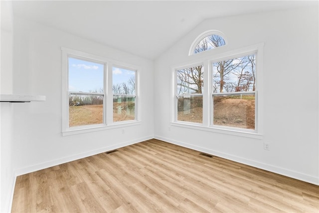 interior space with light wood-type flooring, visible vents, lofted ceiling, and baseboards