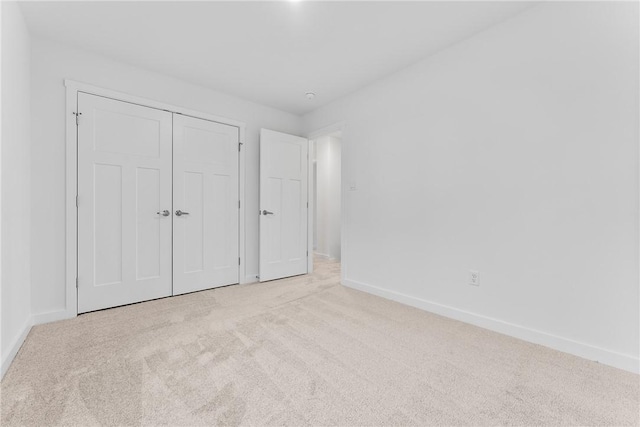 unfurnished bedroom featuring carpet, baseboards, and a closet