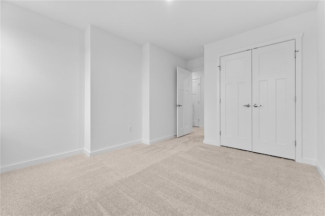 unfurnished bedroom with light carpet, baseboards, and a closet