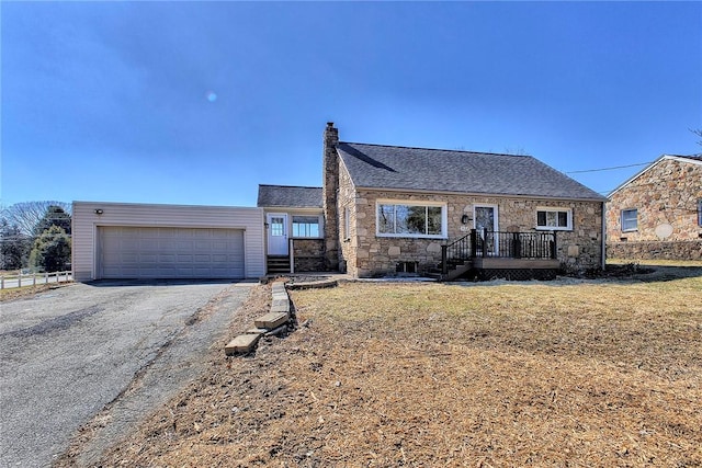 view of front of home featuring a garage, stone siding, a chimney, and a front yard