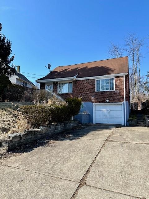 view of front of home featuring concrete driveway, brick siding, and an attached garage