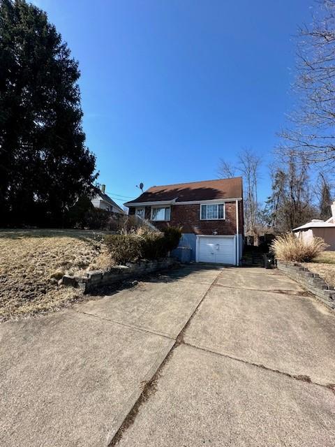 view of front of home featuring a garage, concrete driveway, and brick siding