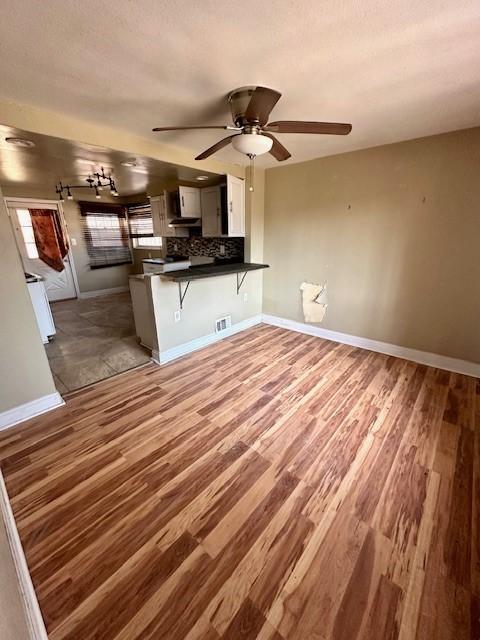 kitchen with visible vents, decorative backsplash, dark countertops, wood finished floors, and a peninsula