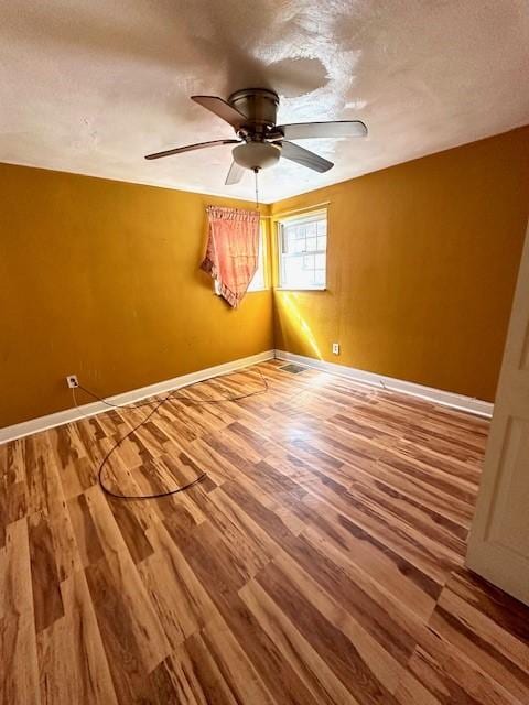 unfurnished room featuring a ceiling fan, a textured ceiling, baseboards, and wood finished floors