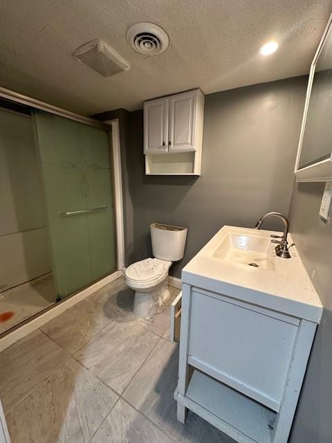 bathroom featuring a textured ceiling, toilet, vanity, visible vents, and a stall shower