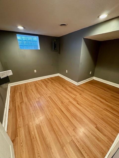 finished basement featuring light wood finished floors, visible vents, and baseboards