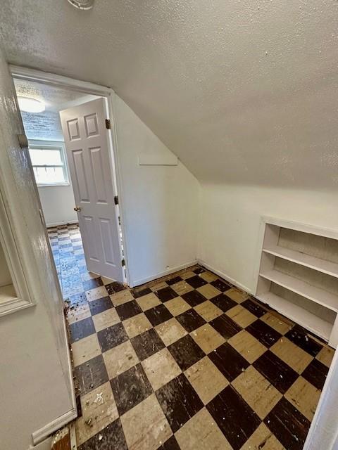 bonus room featuring a textured ceiling, vaulted ceiling, and tile patterned floors