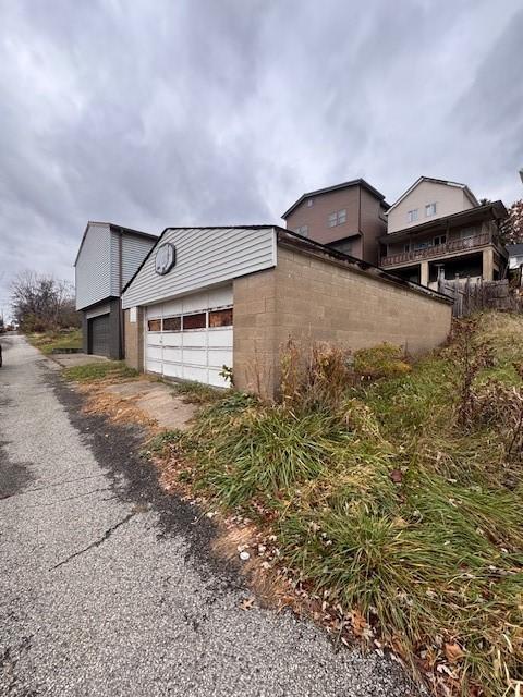 view of side of home with an outbuilding, concrete block siding, and a garage