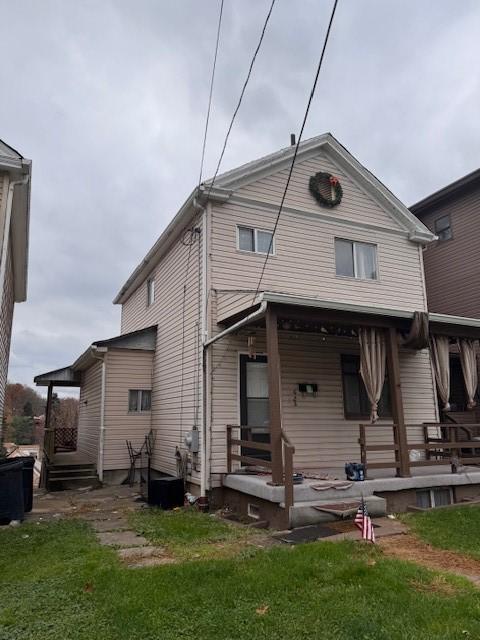 back of property featuring covered porch and a yard