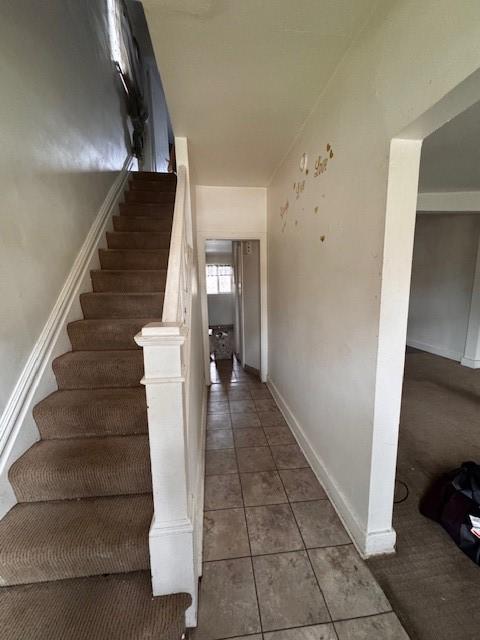 stairs with baseboards and tile patterned floors