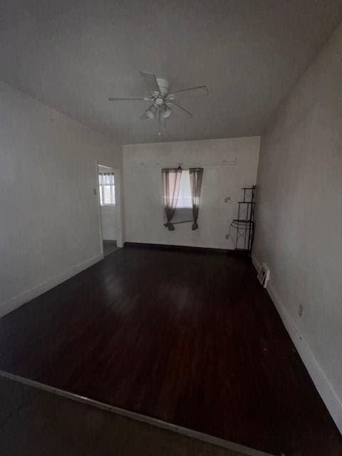 empty room with a ceiling fan, baseboards, and wood finished floors