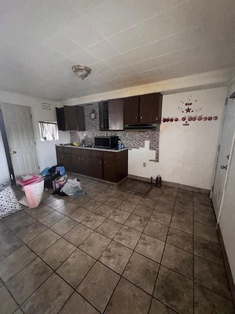 kitchen with dark brown cabinetry, tasteful backsplash, and dark tile patterned flooring