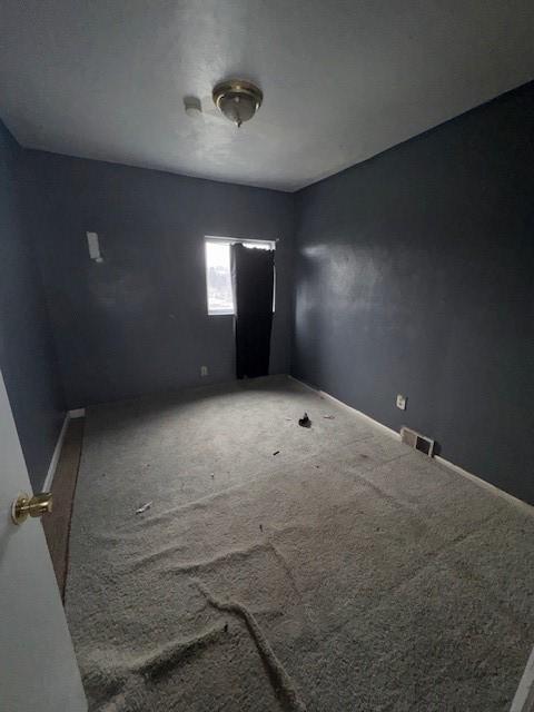 spare room featuring carpet flooring, visible vents, and baseboards