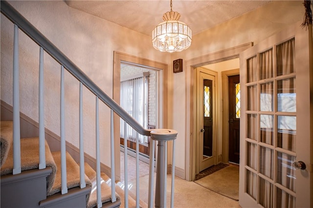 foyer featuring a chandelier, a baseboard radiator, light carpet, and stairway