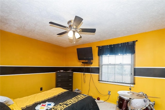 bedroom featuring a wainscoted wall, ceiling fan, and a textured ceiling