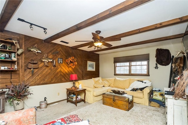 living area featuring wooden walls, a ceiling fan, beamed ceiling, carpet, and track lighting