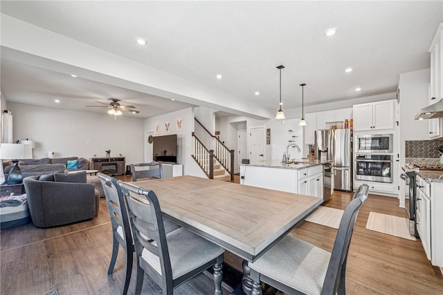 dining room featuring stairway, wood finished floors, a ceiling fan, and recessed lighting