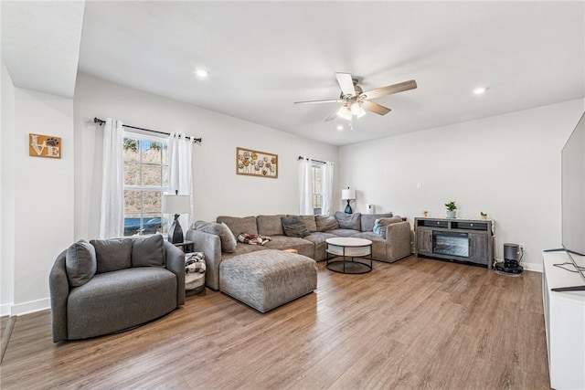 living room with a ceiling fan, light wood-type flooring, and baseboards