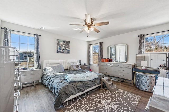 bedroom with visible vents, ceiling fan, multiple windows, and wood finished floors