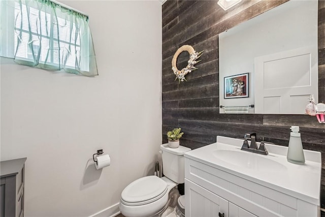 bathroom with vanity, toilet, and wooden walls