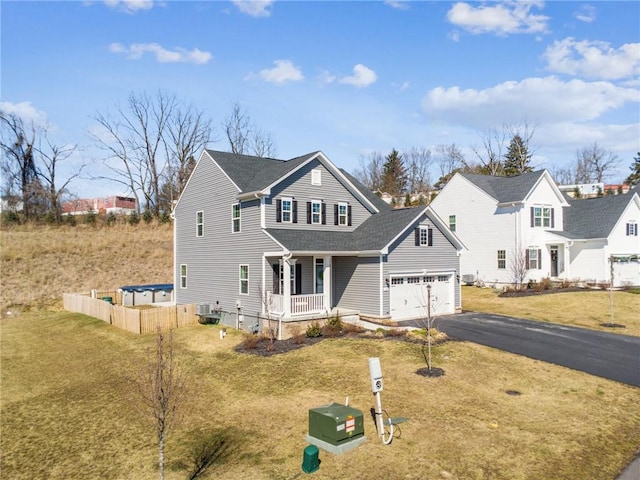 traditional-style home featuring a porch, aphalt driveway, central AC, fence, and a front yard