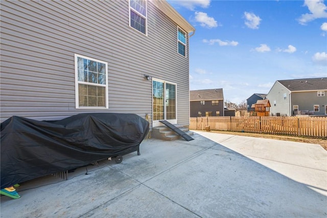 view of patio featuring entry steps, fence, a residential view, and a grill