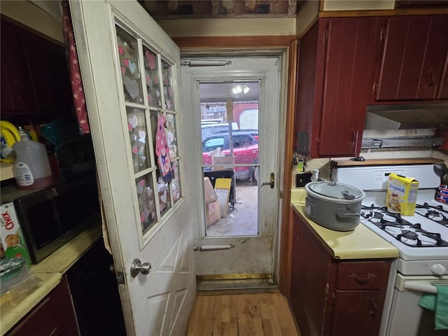 interior space featuring light countertops, stainless steel microwave, white range with gas cooktop, light wood-type flooring, and under cabinet range hood