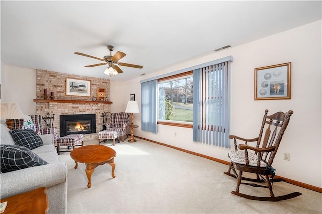 carpeted living area with a ceiling fan, a brick fireplace, visible vents, and baseboards