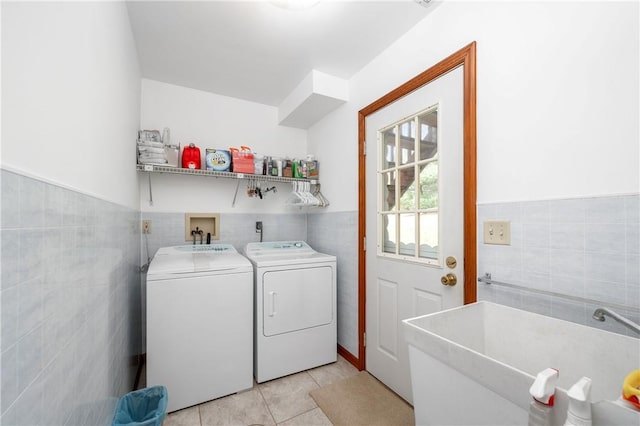 laundry area featuring light tile patterned floors, a wainscoted wall, laundry area, separate washer and dryer, and tile walls