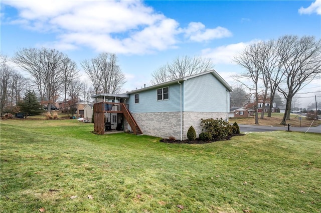 back of property featuring a lawn, a wooden deck, and stairs