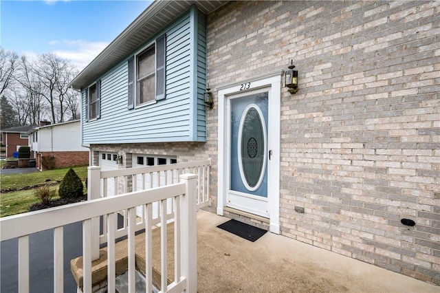 entrance to property with brick siding and an attached garage