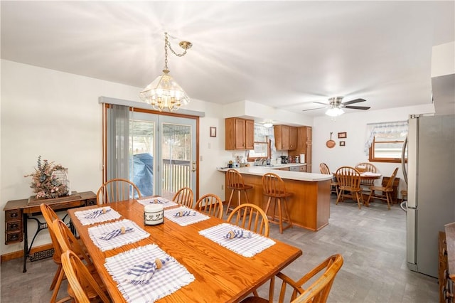 dining room with a wealth of natural light, baseboards, and ceiling fan with notable chandelier