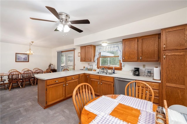 kitchen with brown cabinets, light countertops, stainless steel dishwasher, a sink, and a peninsula