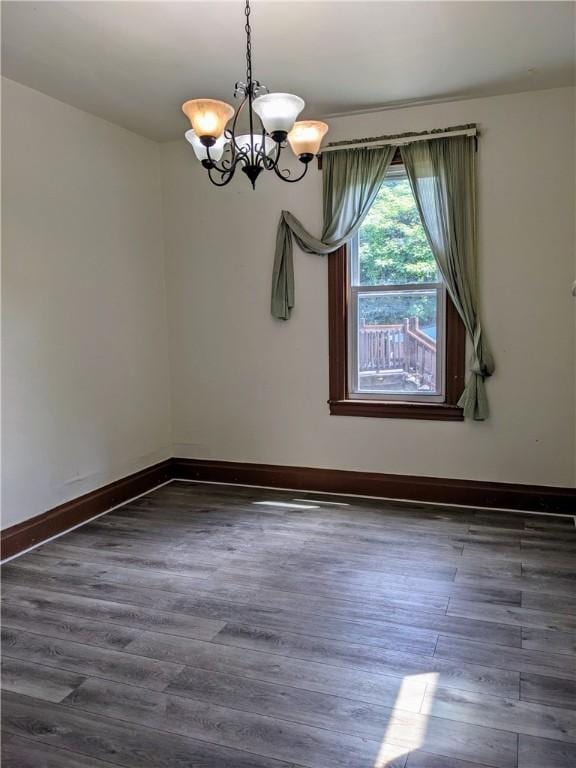 unfurnished dining area with wood finished floors, baseboards, and an inviting chandelier