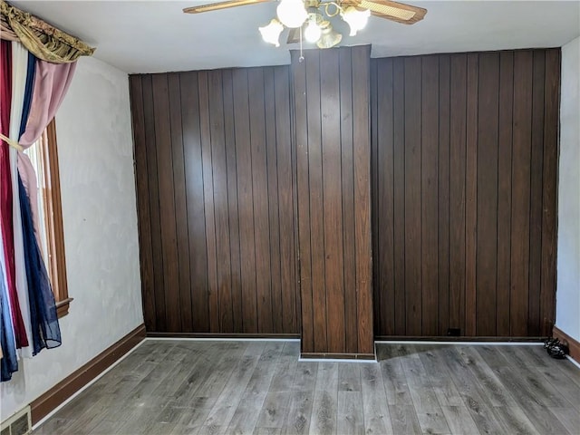 unfurnished room featuring a ceiling fan, wooden walls, visible vents, and wood finished floors