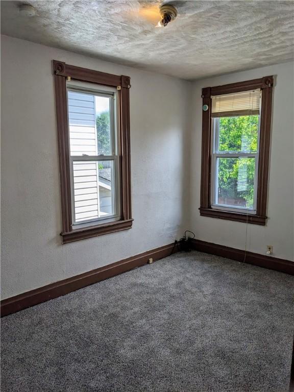 carpeted empty room with a textured ceiling and baseboards