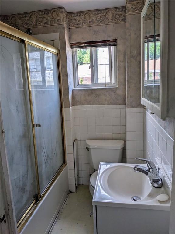 full bathroom with toilet, plenty of natural light, enclosed tub / shower combo, and vanity