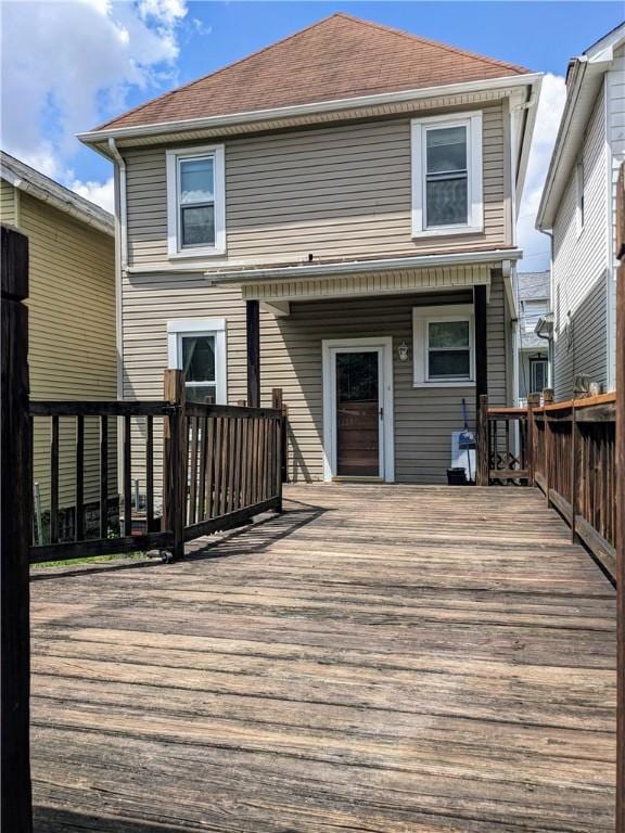 rear view of house featuring roof with shingles and a deck