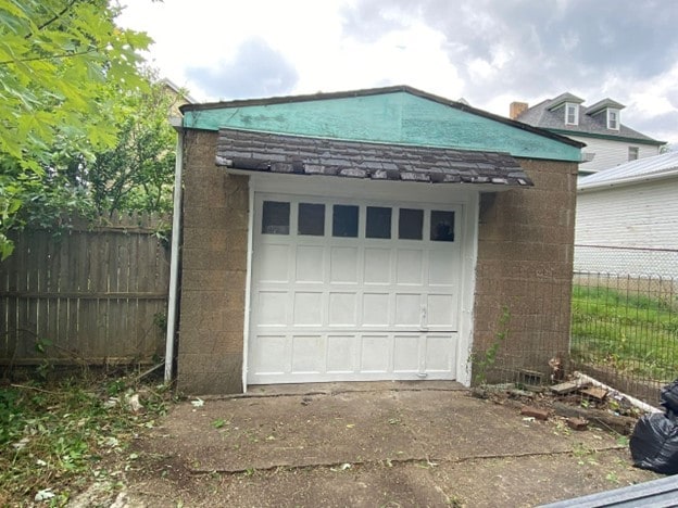 detached garage with concrete driveway and fence