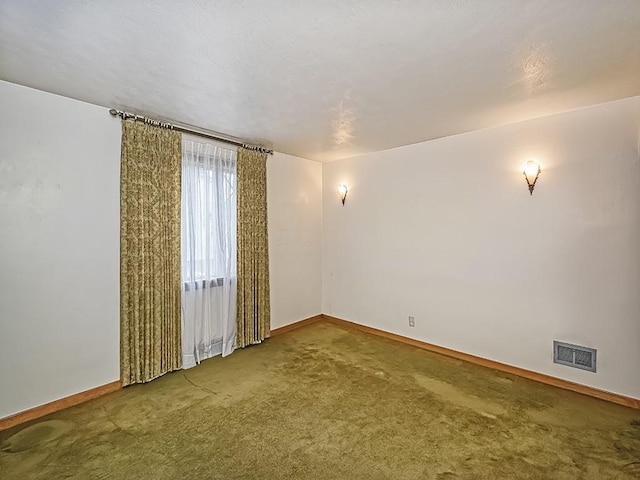 carpeted spare room featuring visible vents and baseboards