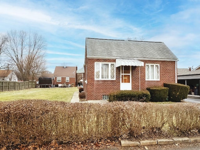 view of front of house with a front yard, brick siding, and fence