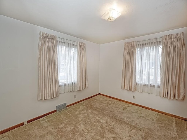 empty room with baseboards, carpet, visible vents, and a wealth of natural light