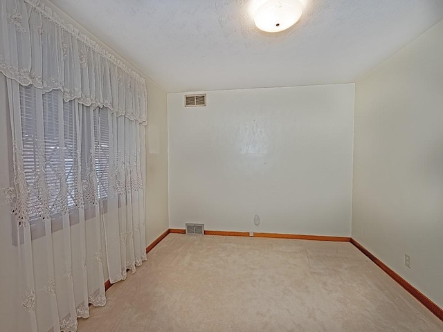 carpeted empty room with visible vents and baseboards